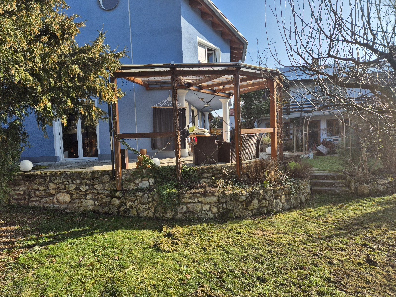 Erhöhte Terrasse mit Natursteinmauer und Pergola